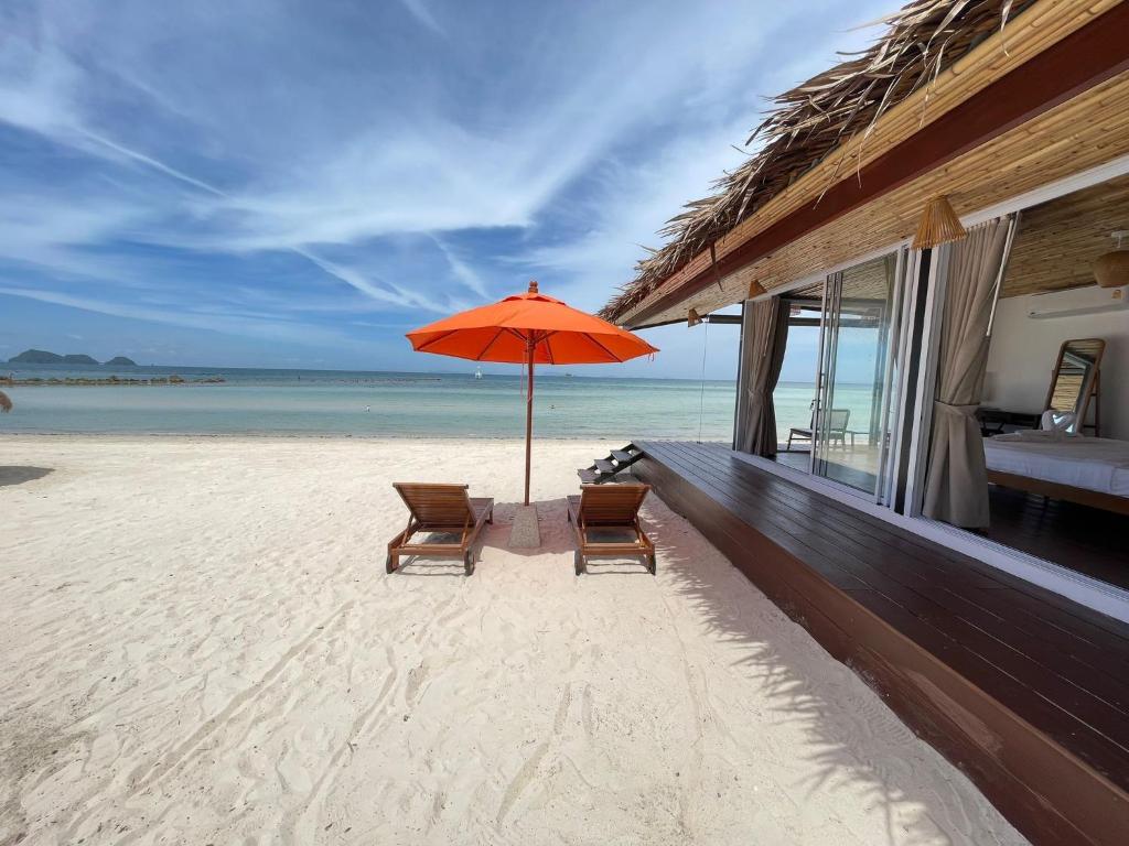 two chairs and an umbrella on the beach at Nice Sea Resort in Srithanu