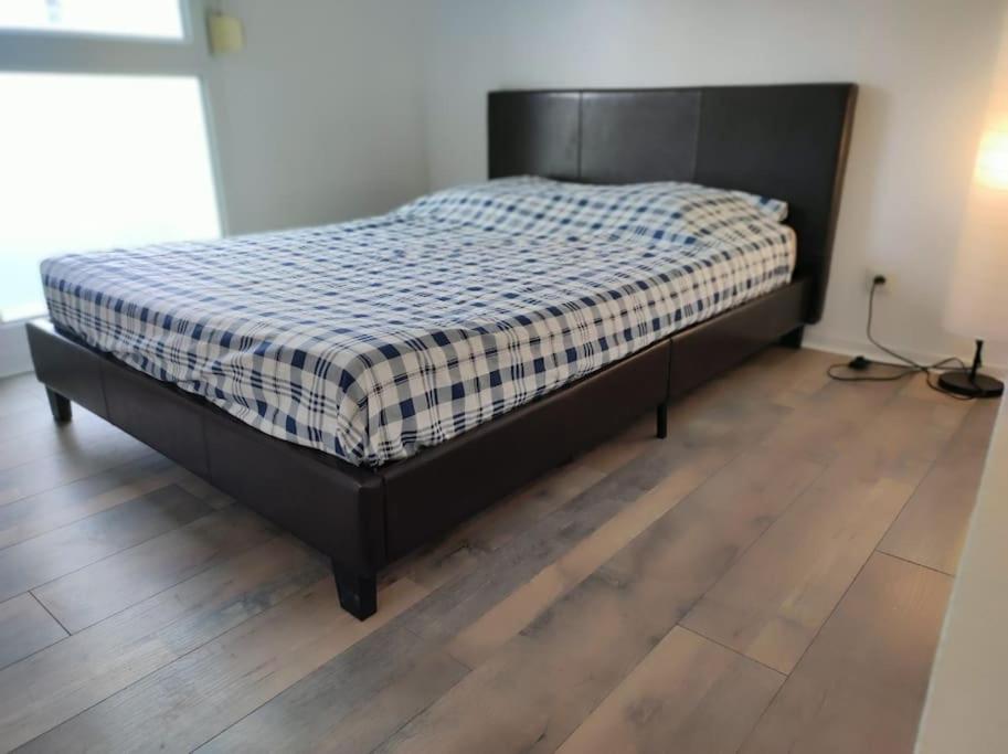 ein schwarzes Bett in einem Zimmer mit Holzboden in der Unterkunft Montereau FY Appt 3P 2 ch Balcon in Montereau-faut-Yonne