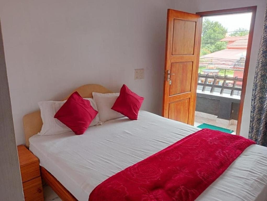una camera da letto con un letto con cuscini rossi e una finestra di OYO Flagship Temple Fort Residency a Alleppey