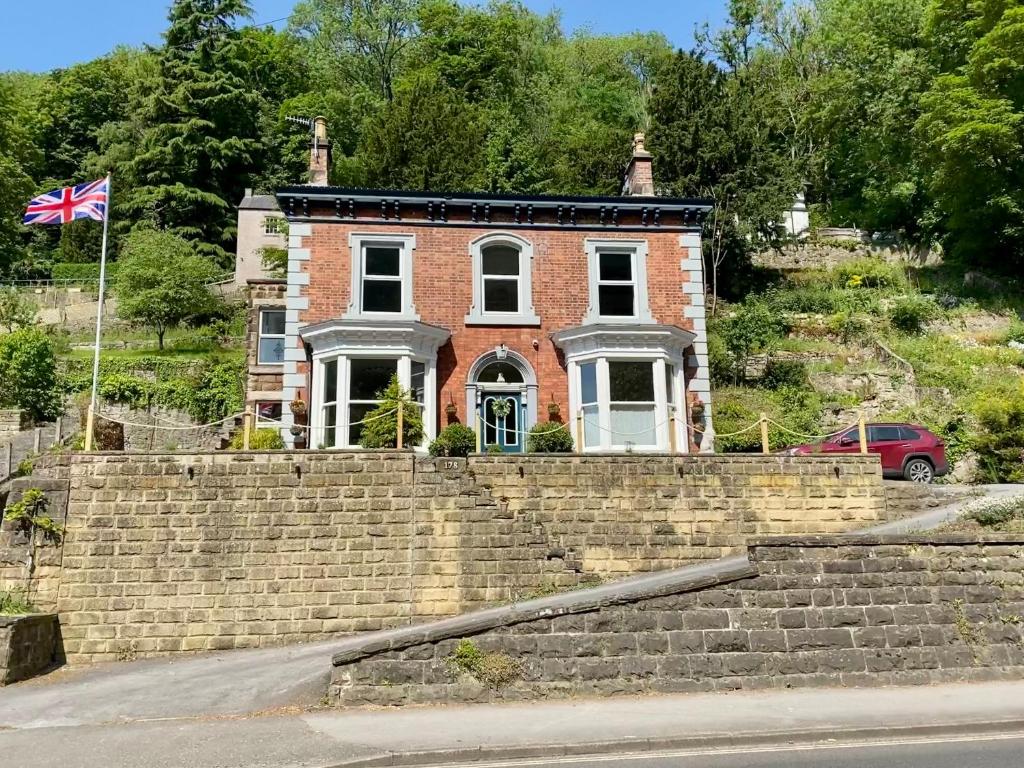 Una casa de ladrillo en una colina con una bandera. en Heathbank House B&B en Matlock Bank