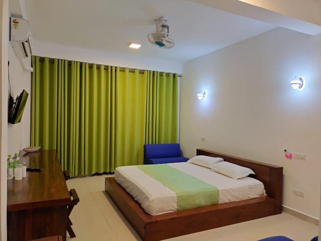 a bedroom with a bed and a green curtain at Hotel Serugahawatta in Wellawaya