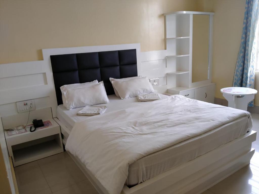sypialnia z dużym białym łóżkiem z czarnym zagłówkiem w obiekcie HOTEL NL7 w Dimapur