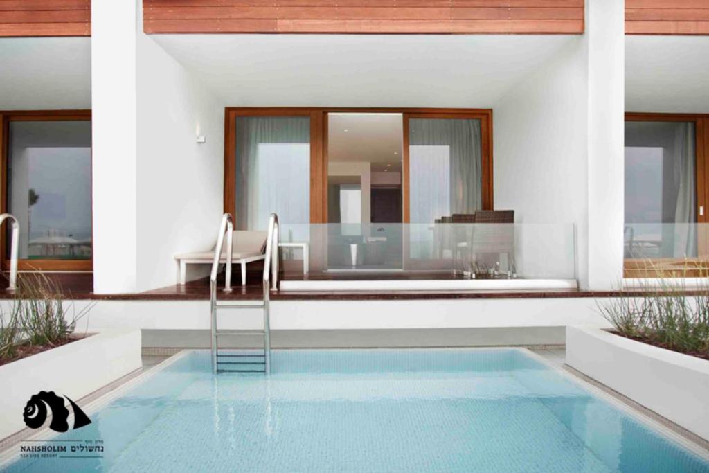 納紹琳的住宿－Nachsholim Beach Hotel，房屋设有1个带桌椅的游泳池