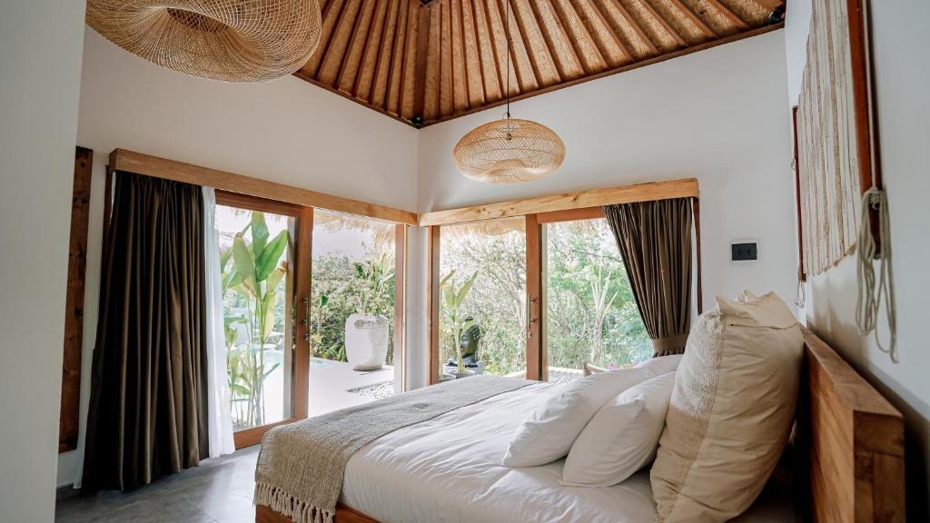 a bedroom with a bed and a large window at petra bianca uluwatu in Uluwatu