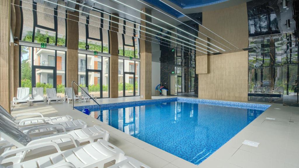 uma grande piscina com cadeiras brancas num edifício em Apartamenty Sun & Snow Baltic Apartments z basenem em Pobierowo