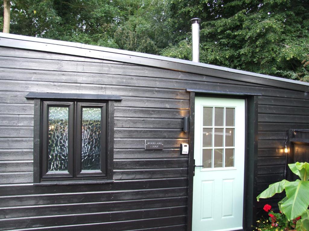 een houten hut met een deur en een raam bij Charming 1-Bed Lodge in woodland setting in Great Yarmouth