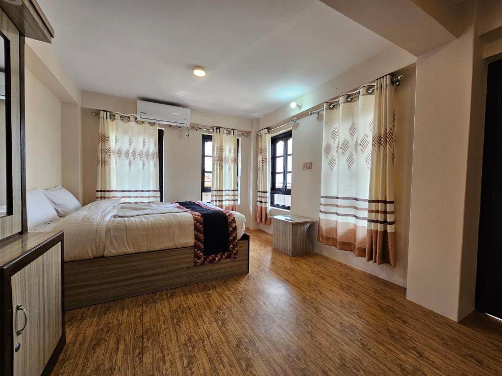 a bedroom with a bed and two windows at Hotel Durbar Side in Bhaktapur