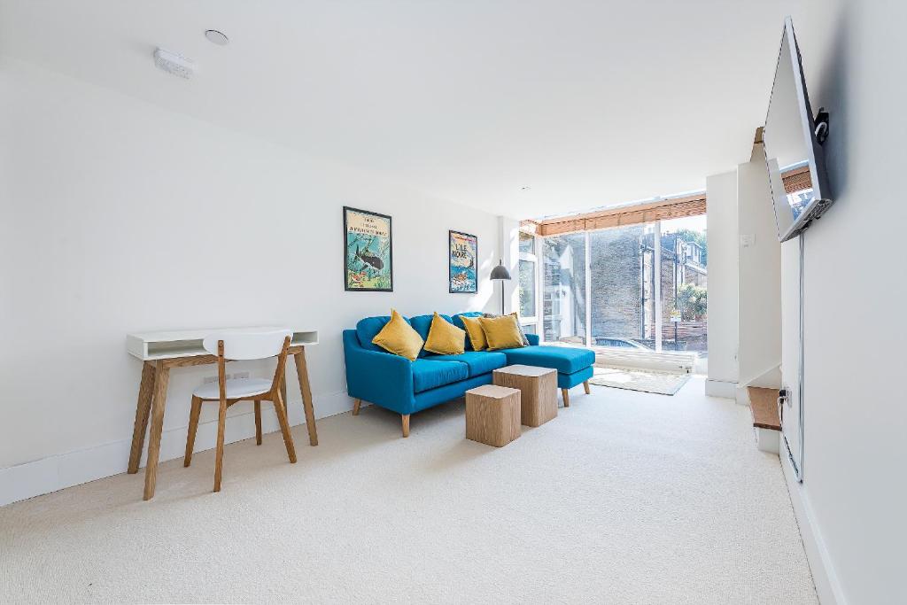a living room with a blue couch and a table at Hidden Gem in Chiswick, Stylish 1 Bedroom House in London