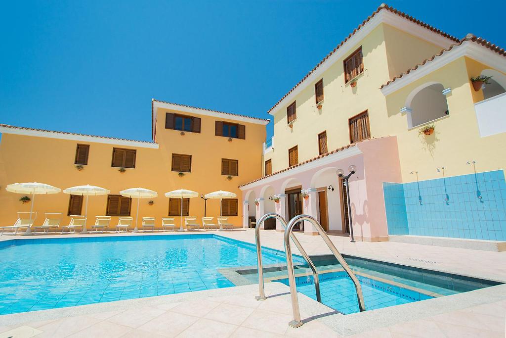 a swimming pool in front of a building at ISA - Residence with swimming pool in Sos Alinos, apartments with air conditioning and private outdoor area in Cala Liberotto