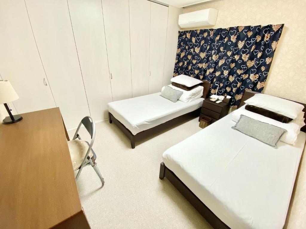 Habitación con 2 camas, escritorio y silla. en Reynaville 4F / Vacation STAY 2134, en Tokushima