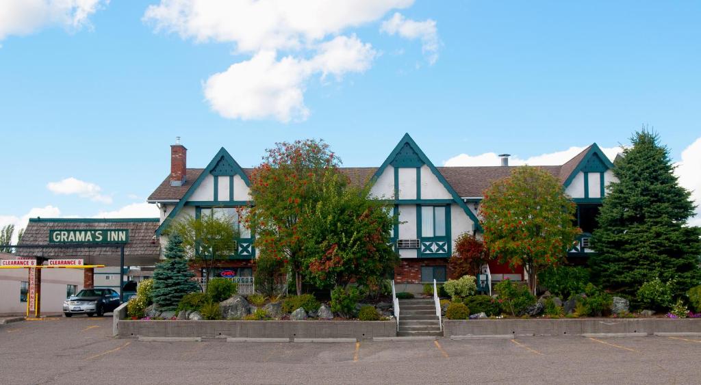 a building in a parking lot with trees in front of it at Grama's Inn in Prince George