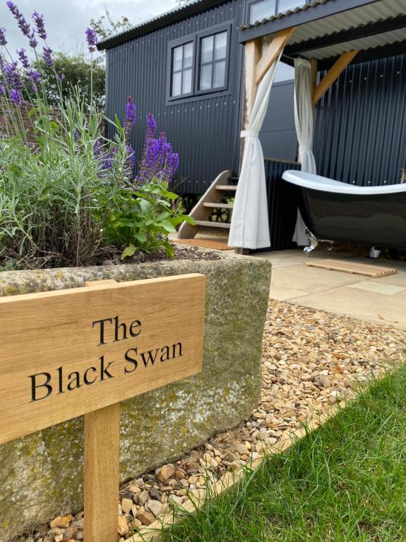 a sign that reads the black swan in a garden at The Black Swan Shepherd Hut in Ketton