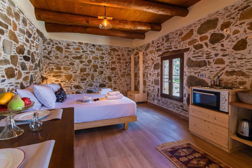a bedroom with a bed in a room with stone walls at Plagia Rooms in Kissamos