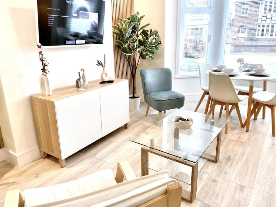 ein Wohnzimmer mit Fernseher und Tisch und Stühlen in der Unterkunft Lush Porthcawl Large Spacious 2 bedroom Apt, Parking, Garden access, Prime Location in Porthcawl