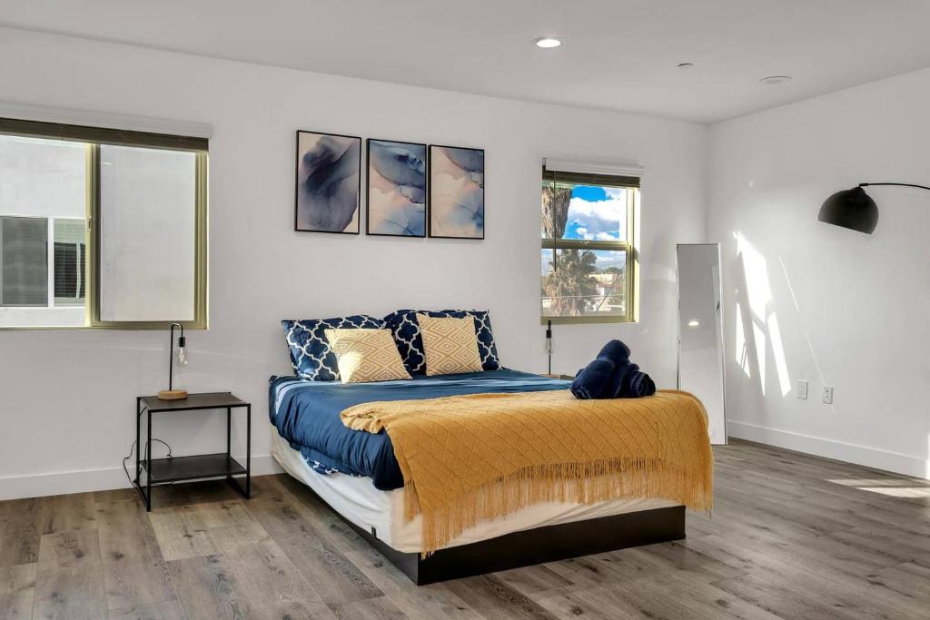 um quarto com uma cama com um cobertor azul e duas janelas em Wonderful 3 Bedroom Home Perfect for Getaway em Los Angeles