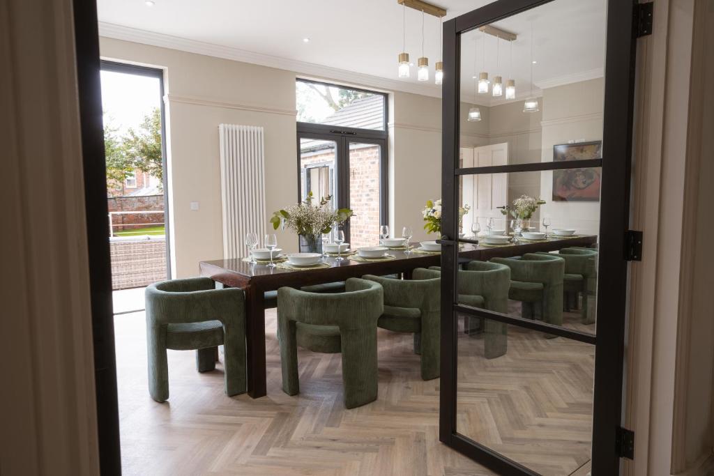 una sala da pranzo con un tavolo e sedie verdi di Our House Collective - Luxury Stay in Lincoln City Centre, Hot tub, Sleeps 16 a Lincoln