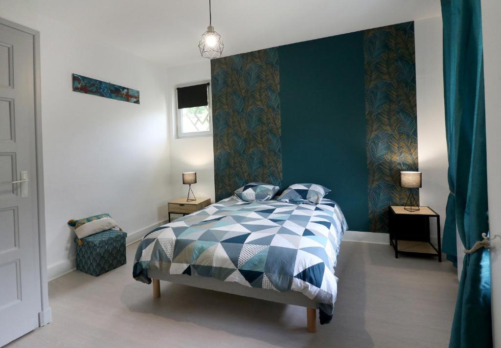 a bedroom with a bed with a blue wall at La Marionnade - Maison de village, Sauna, Balnéothérapie, Borne VE in Cerdon