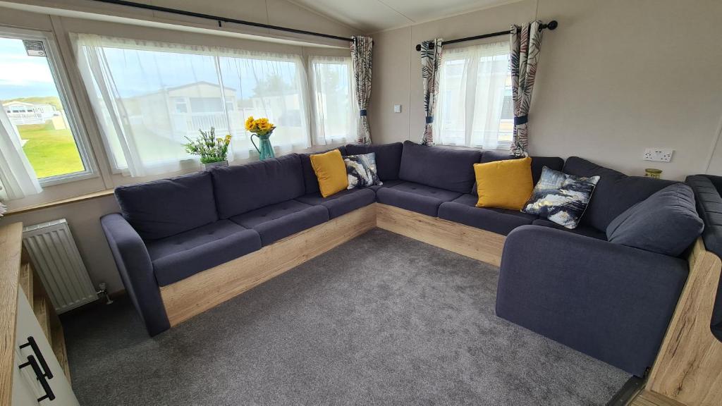a living room with a blue couch and yellow pillows at Madaisy in Lossiemouth