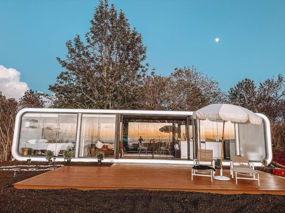 ein modernes Haus mit einer Terrasse mit Stühlen und Tischen in der Unterkunft Modern Off Grid Tiny Home! in Haleiwa