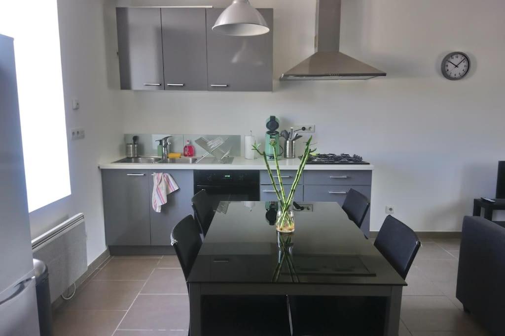 une cuisine avec une table avec un vase de fleurs dessus dans l'établissement Bel appart duplex moderne à 9 min de l'aéroport, à Janneyrias