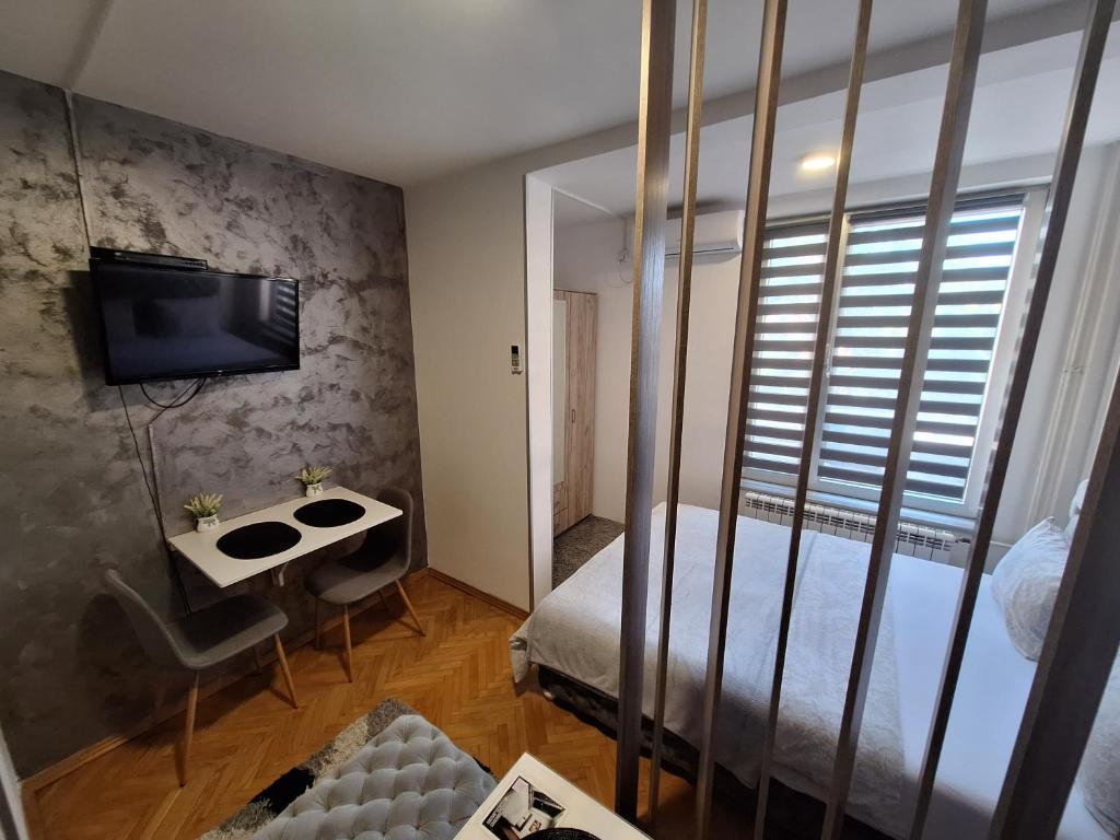um quarto com uma cama, uma mesa e uma televisão em Dado apartman em Kraljevo