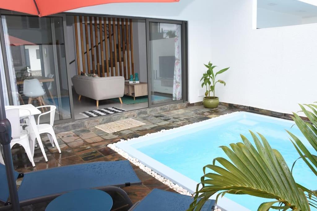 uma piscina numa sala de estar com um guarda-sol em la falaise paradis Mauritius em Flic-en-Flac