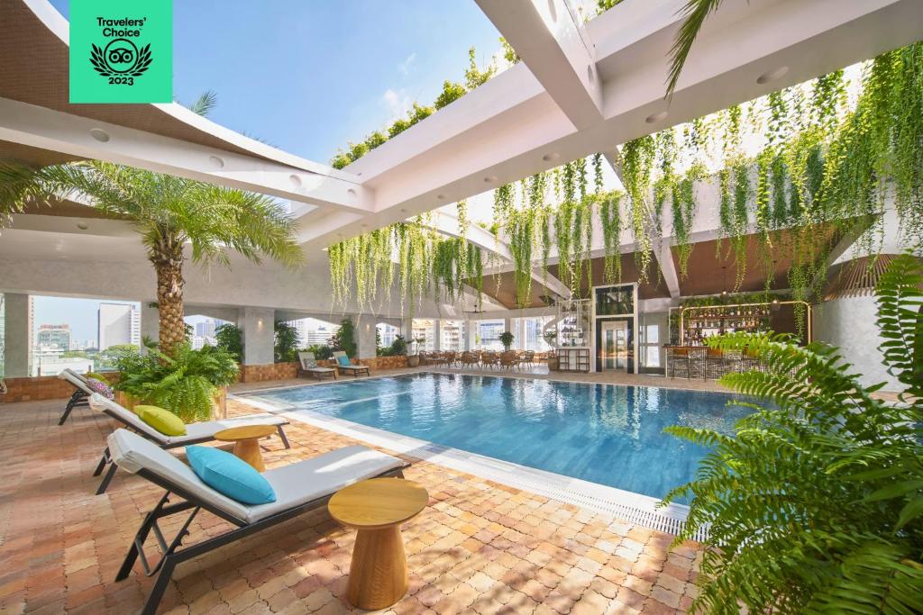 an indoor pool in a building with chairs and plants at Silverland Mây Hotel in Ho Chi Minh City