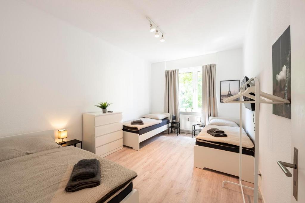 Work & Stay in Mannheim في مانهايم: غرفة نوم بيضاء بسريرين ومكتب