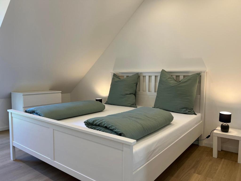 a white bed with green pillows on top of it at Heide-Liebe in Soltau