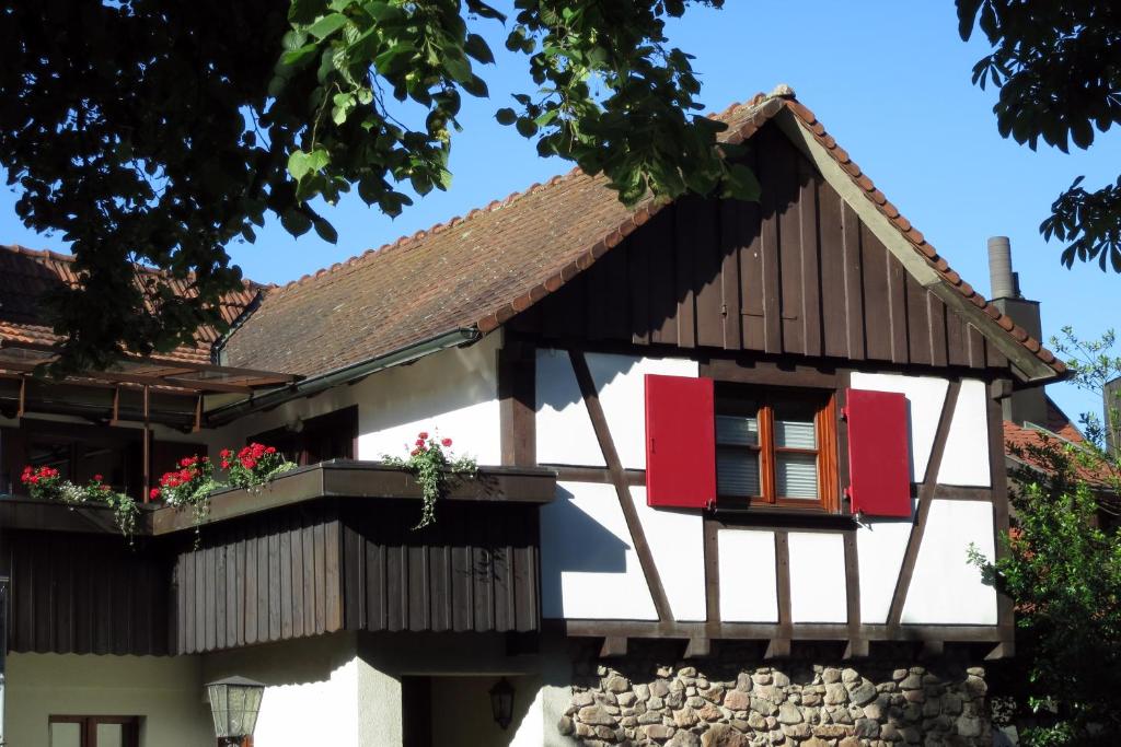 a house with red windows and a stone wall at Ferienwohnung Sester in Gengenbach