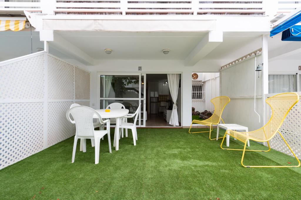 eine Terrasse mit grünem Gras sowie einem Tisch und Stühlen in der Unterkunft Las Adelfas South Beach 2 By CanariasGetaway in San Bartolomé de Tirajana
