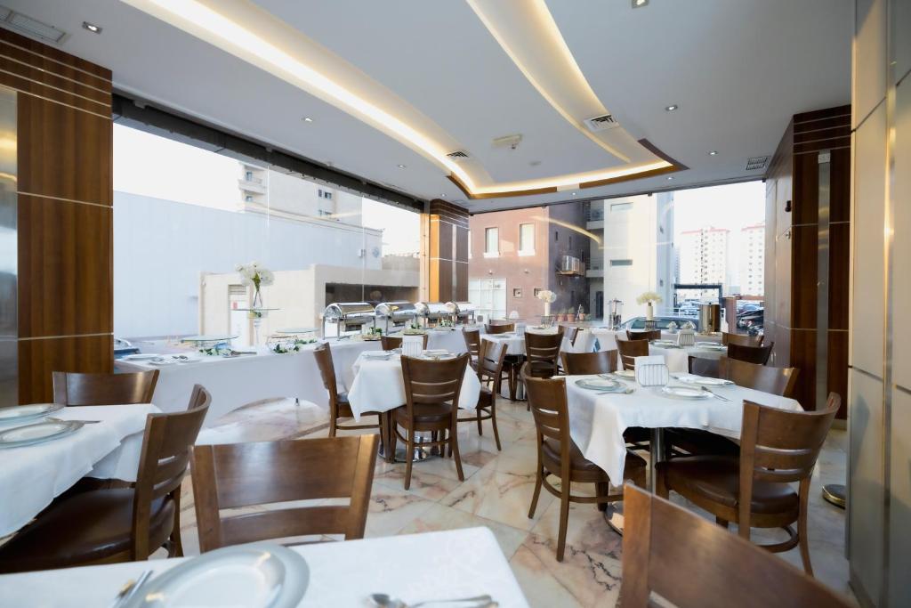 لاغونا هوتيل سويتس  في الكويت: غرفة طعام مع طاولات وكراسي بيضاء