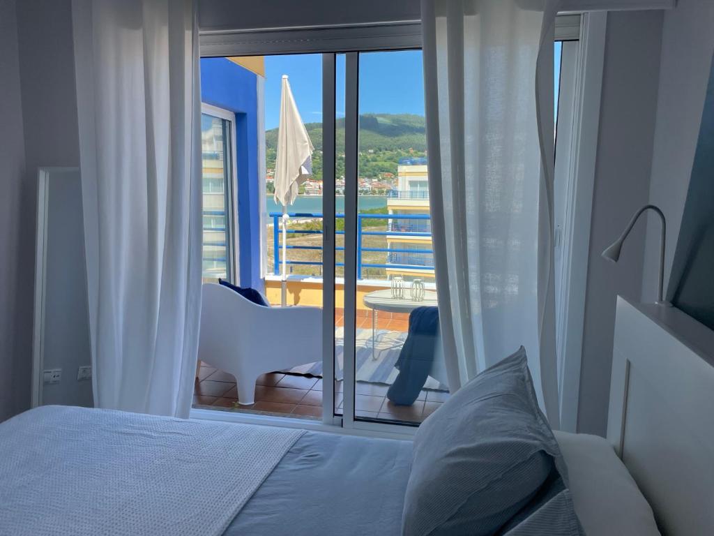 a bedroom with a bed and a view of a balcony at Apartamento con vistas al mar B5 Urb Puerto Azul in Cedeira