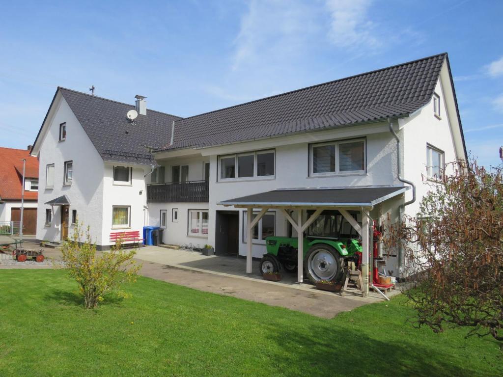a white house with a tractor parked in the driveway at Ferienhaus Rosswangen in Balingen