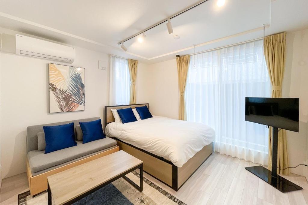 a bedroom with a bed and a couch and a television at Quador Waseda in Tokyo