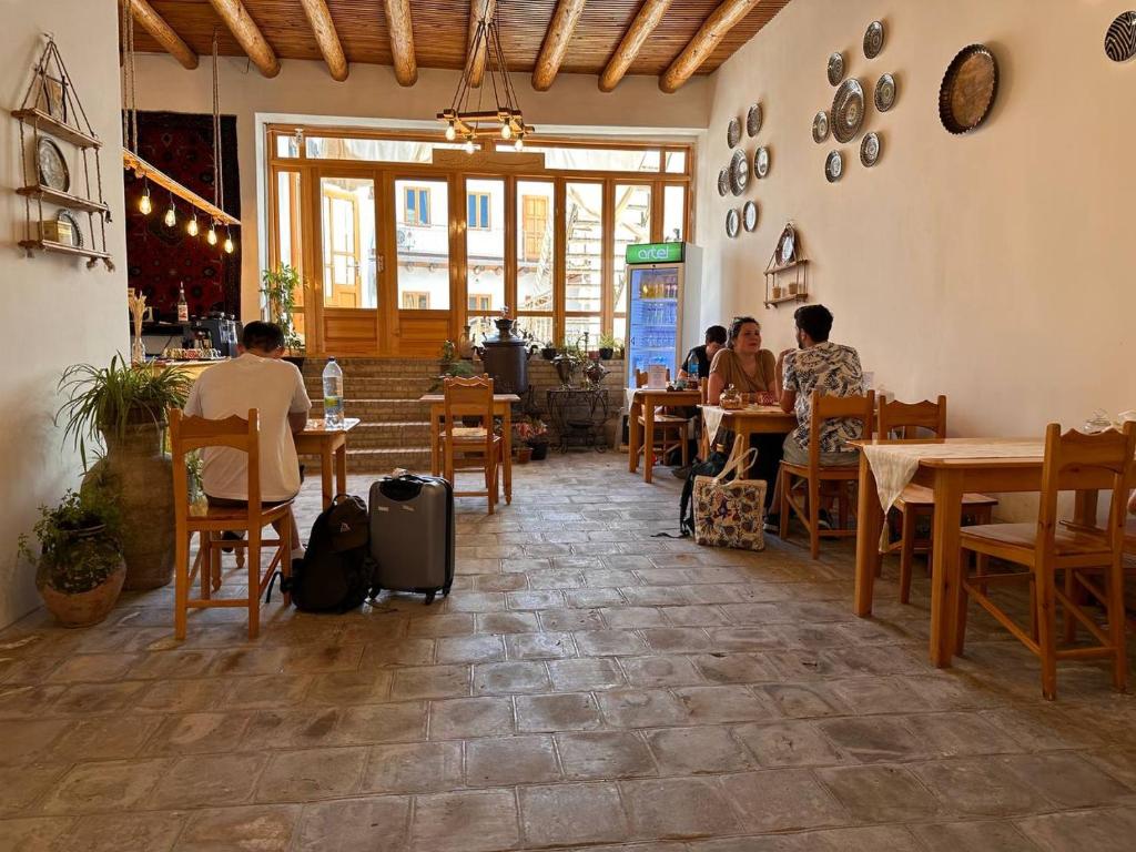 a group of people sitting at tables in a restaurant at Sarrafon Guest House in Bukhara