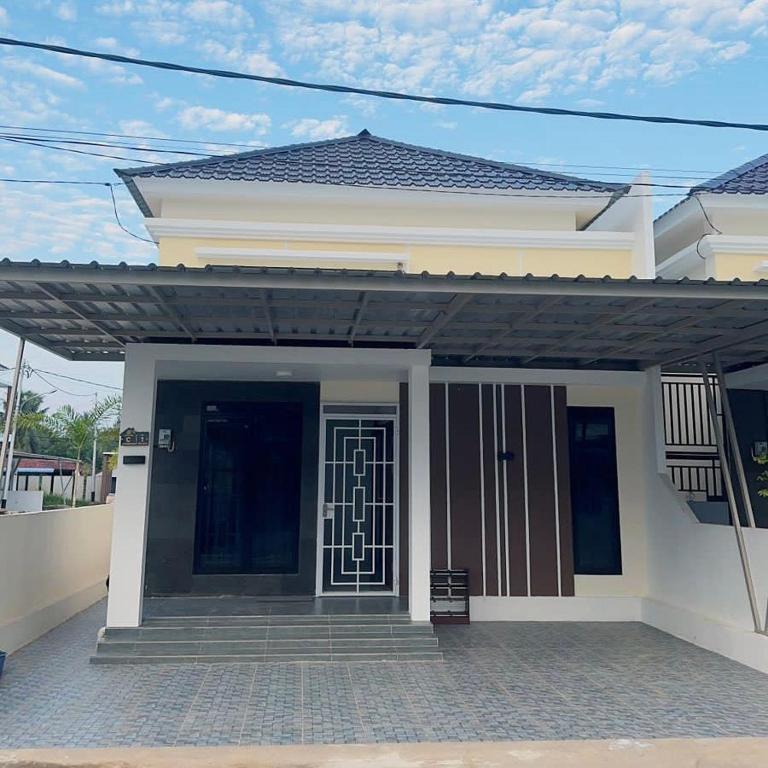 una casa bianca con un cancello e una porta di Holiday Homestay Singkawang a Sedau