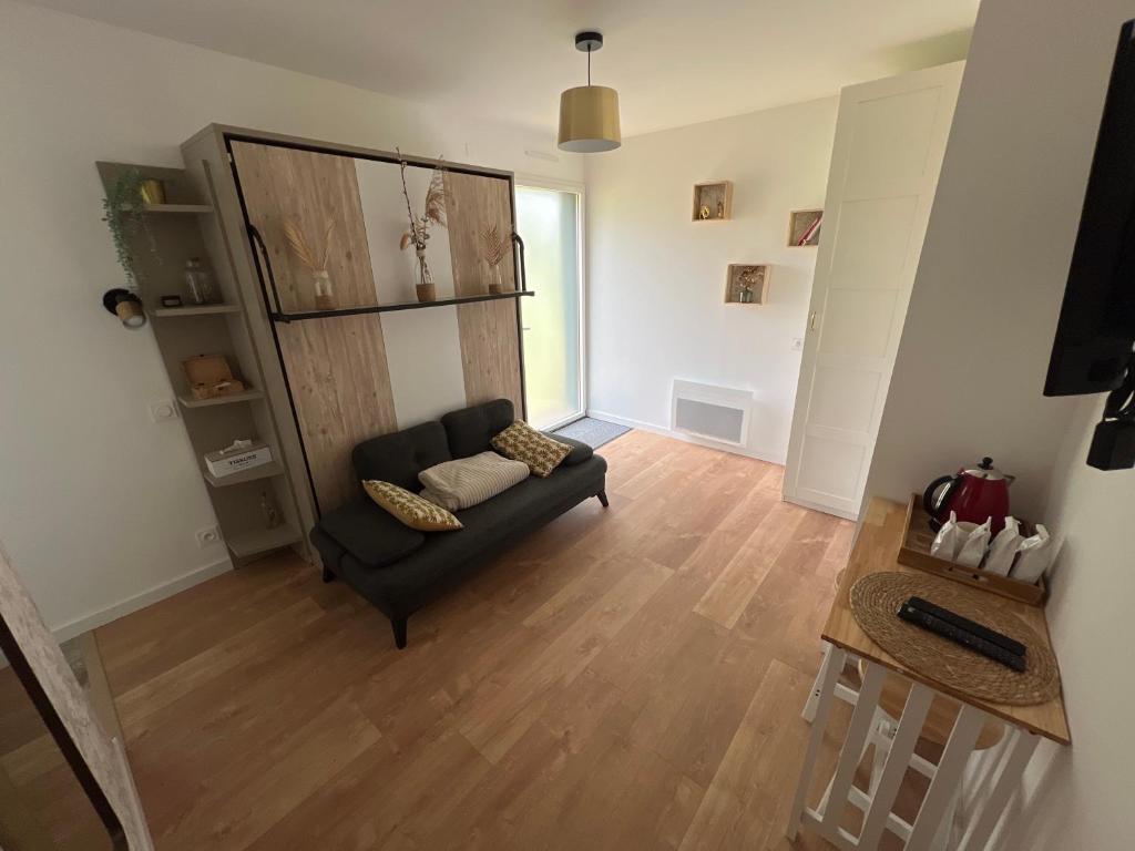 uma sala de estar com um sofá preto e pisos em madeira em Chambre privée avec SDB et WC 