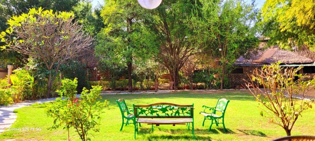 een park met een bank en stoelen in het gras bij Lohagarh Corbett Resort in Belparāo