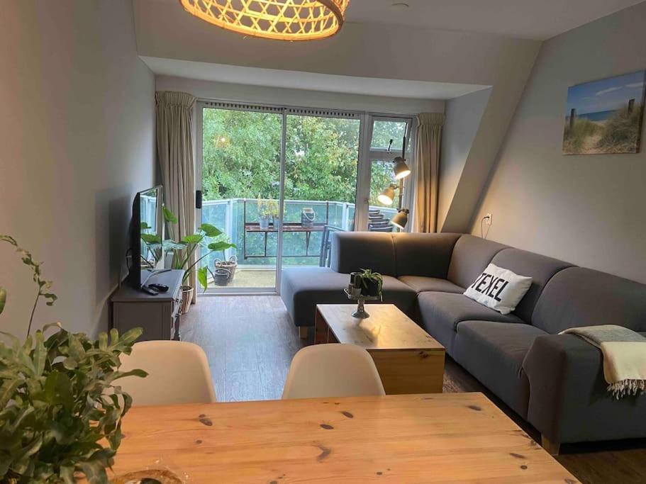 a living room with a couch and a table at Heerlijk appartement op Texel vlakbij bos en zee. in De Koog