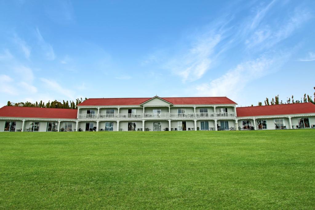 un grand bâtiment avec une pelouse devant lui dans l'établissement Kerikeri Park Lodge, à Kerikeri