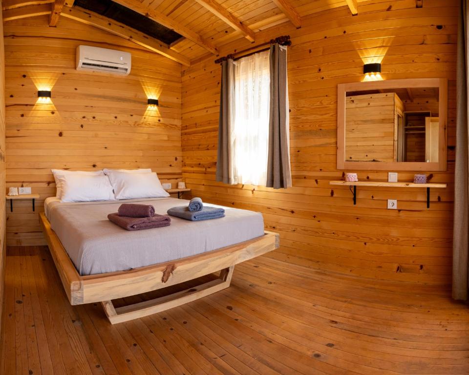 1 dormitorio con 1 cama en una habitación de madera en Goat Bungalow and Camping, en Faralya