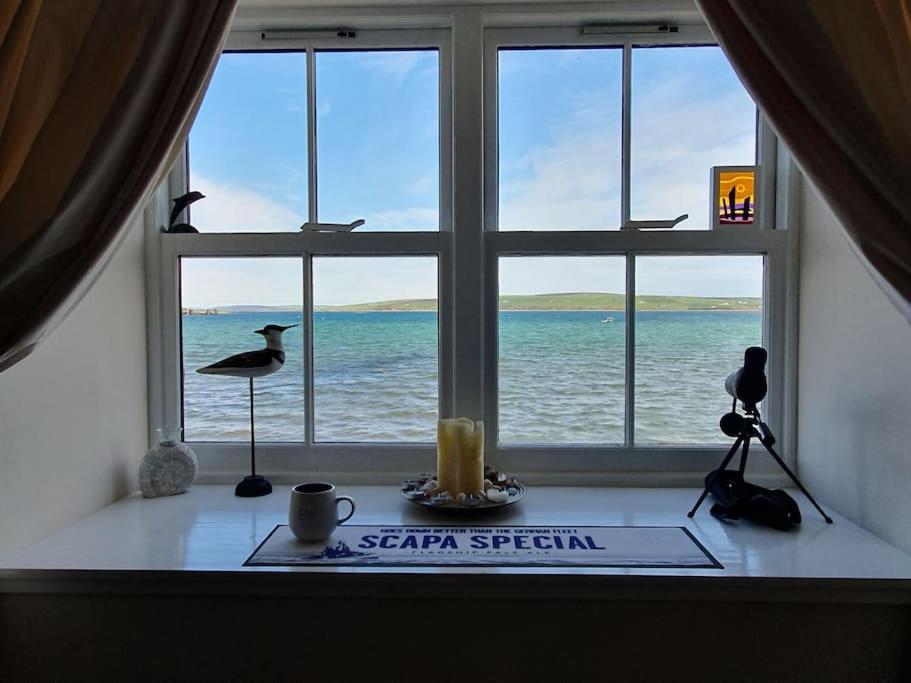 a window with a view of the ocean and a candle at Waterfront Apartment, St Margarets Hope, Orkney in St Margaret's Hope