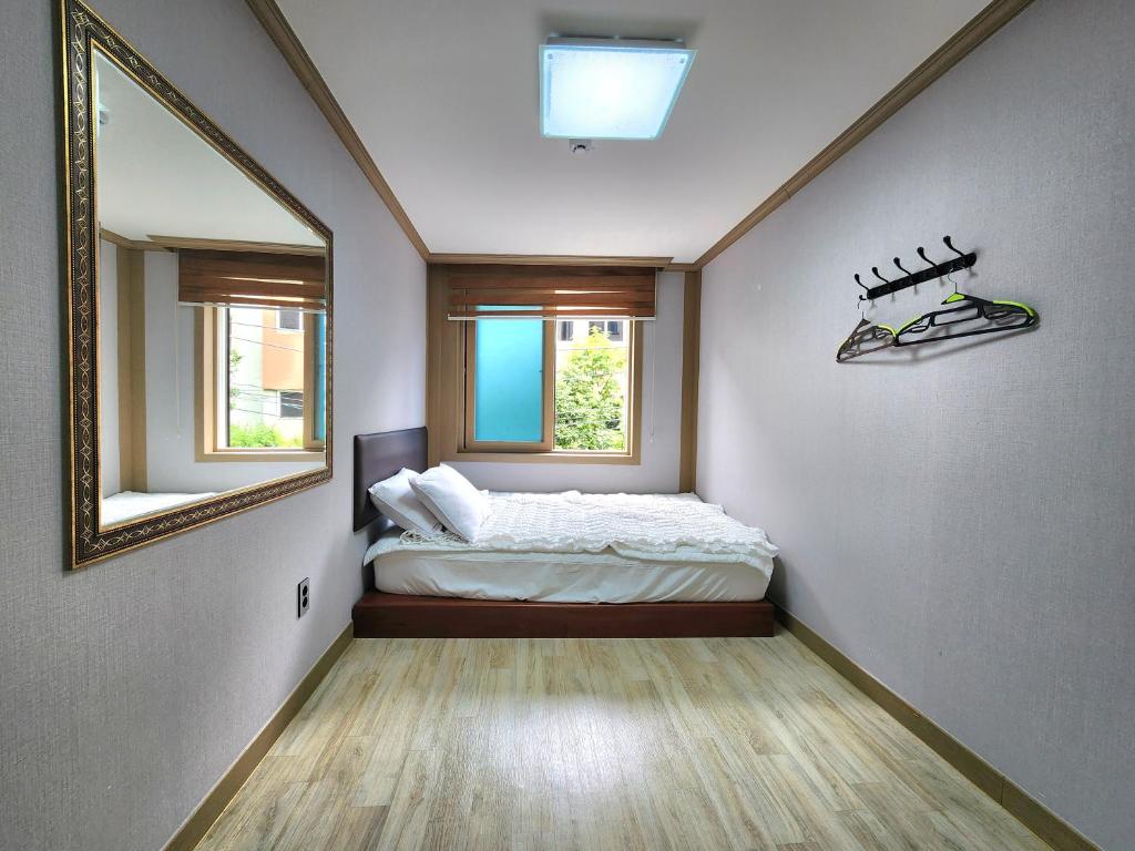 a small bedroom with a bed and a mirror at e comfy Hotel in Ulleung