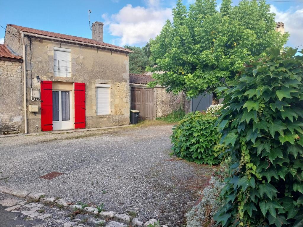 una casa vieja con una puerta roja en una calle en Gite chez Lea, en Saint-Seurin-de-Cadourne