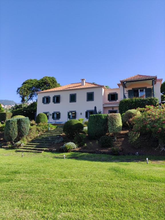 uma grande casa branca com um jardim de relva em Quinta São Gonçalo em Funchal