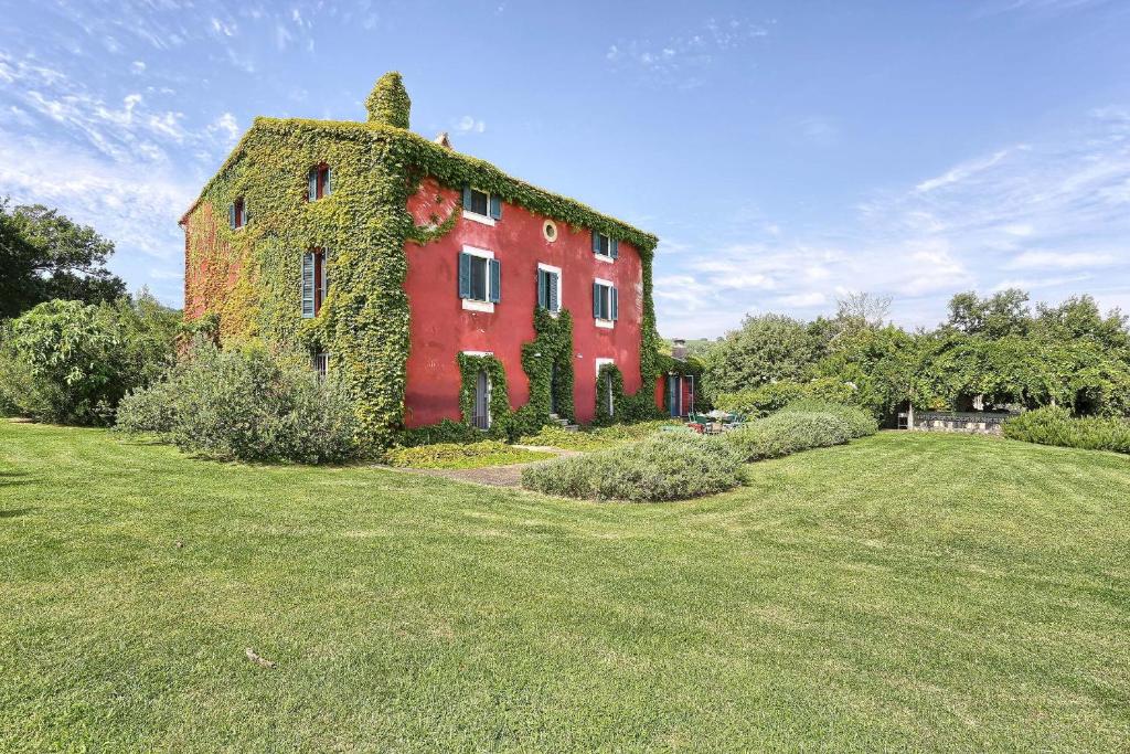 een rood gebouw met klimop op in een veld bij Casa Rossa in Bolsena