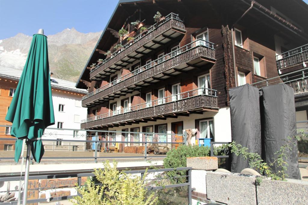 un edificio con una sombrilla delante de él en Self service Guesthouse Berggeist, en Saas-Fee