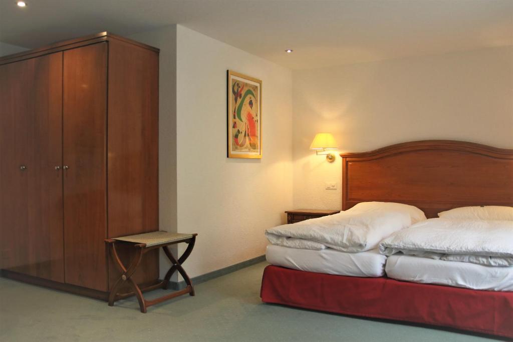 a hotel room with a bed and a cabinet at Self-Service Guesthouse Berggeist in Saas-Fee