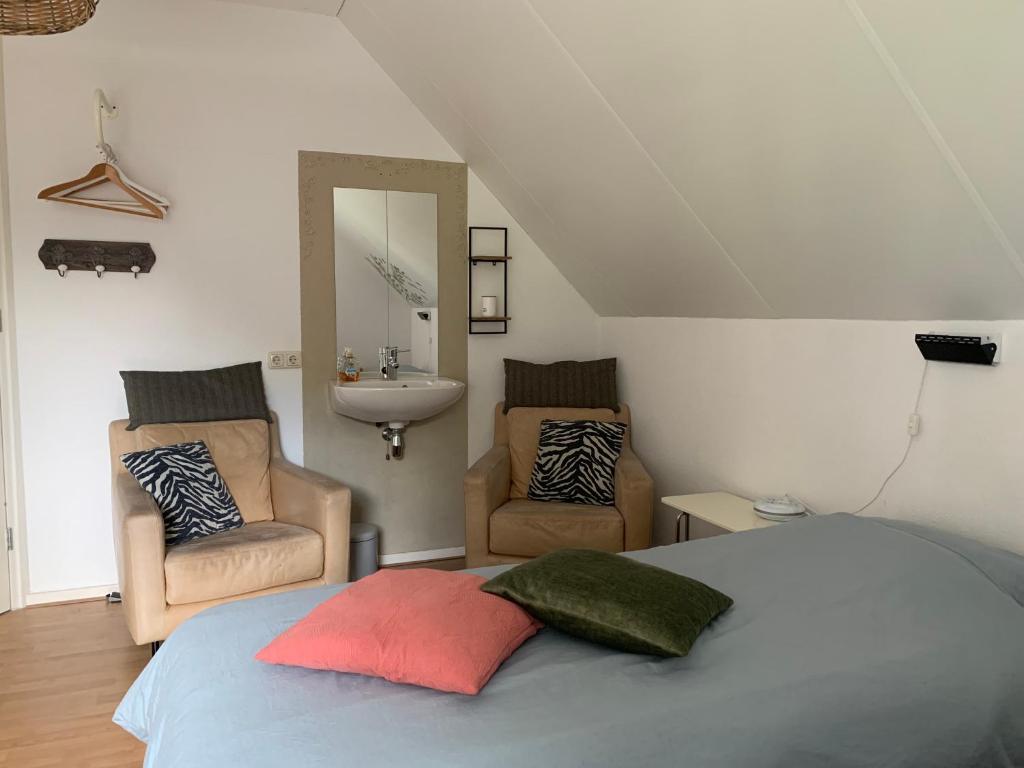 a bedroom with a bed and two chairs and a sink at Brinkesdiek in Hardenberg